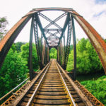 First Career Job: Image is Train Tracks leading through opened sided tressle bridge