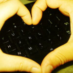 Human Touch: Image is fingers making a heart shape above a keyboard.