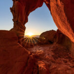 Stay Motivated. Image is a red rock arch with the sun rising through it.