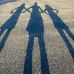 Stop Naysayers: Image is shadow image of three people on a road.